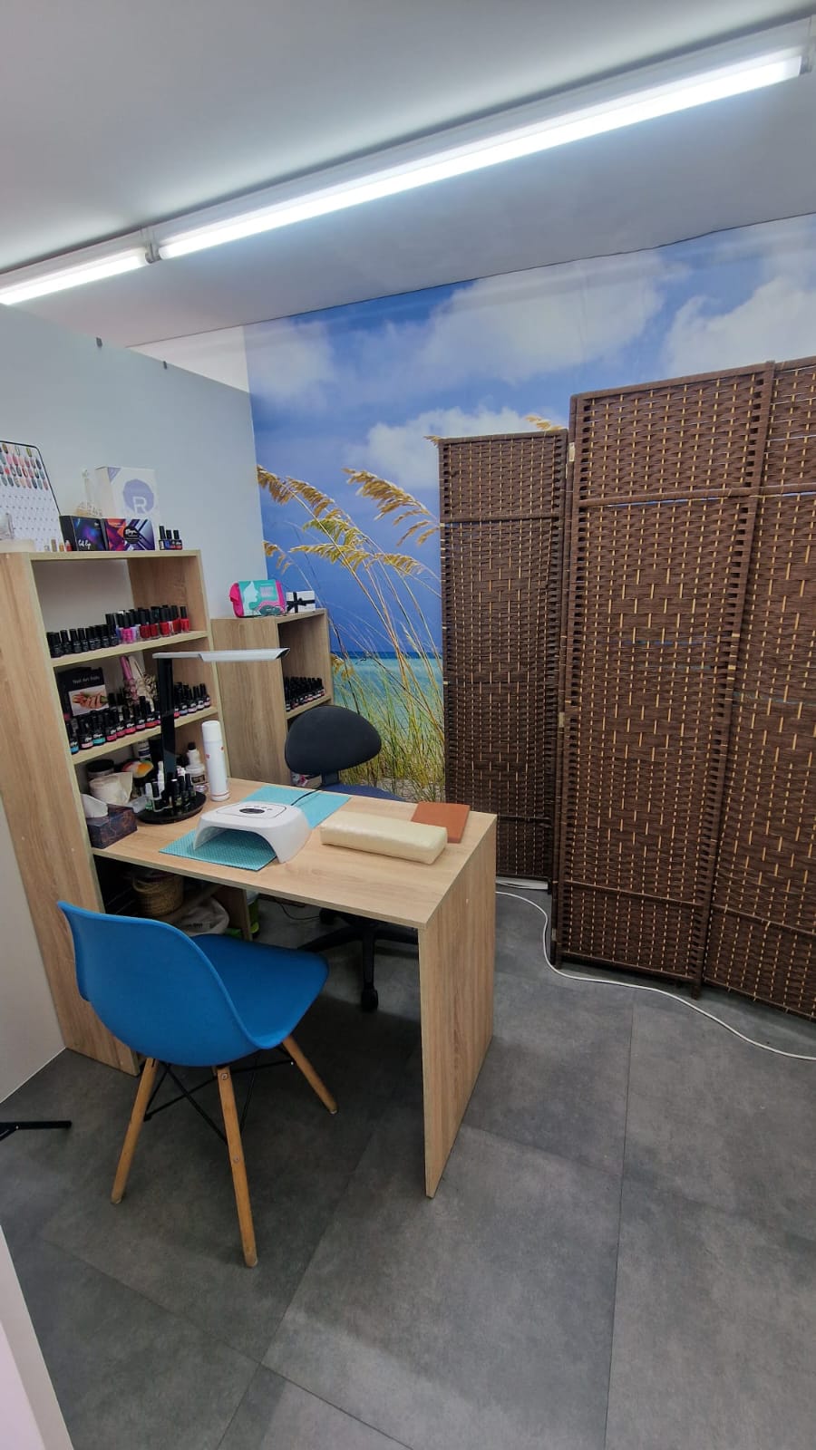 Sala de manicura de Salon Chic Marian con estantería de esmaltes y mural de playa